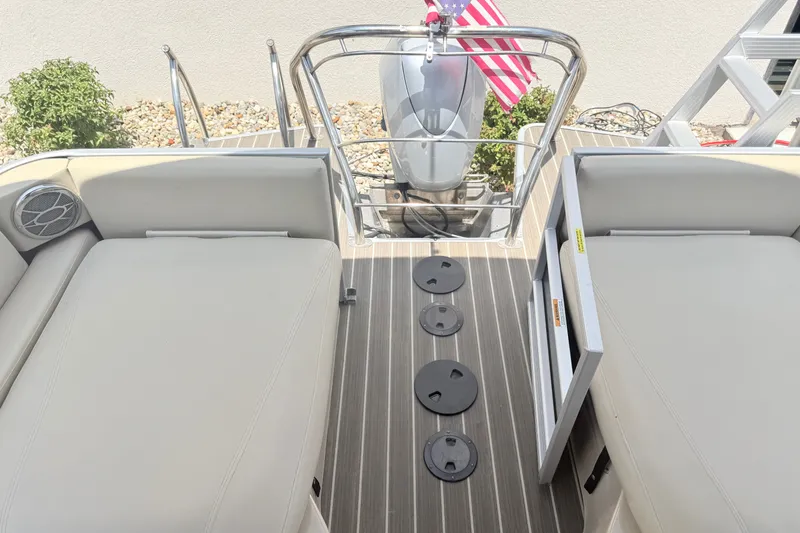 Slide: The Image of 2013 AquaPatio 240 RS boat interior with seating, deck, and American flag. - 18