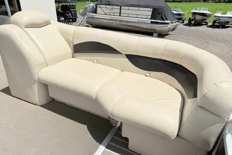 Slide: The Image of 2013 AquaPatio 240 RS boat with beige leather seating, parked near other boats. - 11