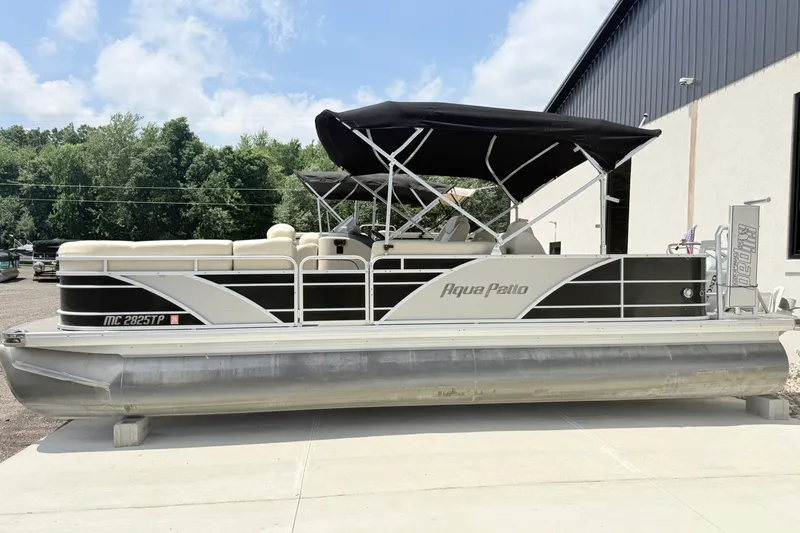 The Image of 2013 AquaPatio 240 RS pontoon boat with black canopy, parked outdoors. - 0