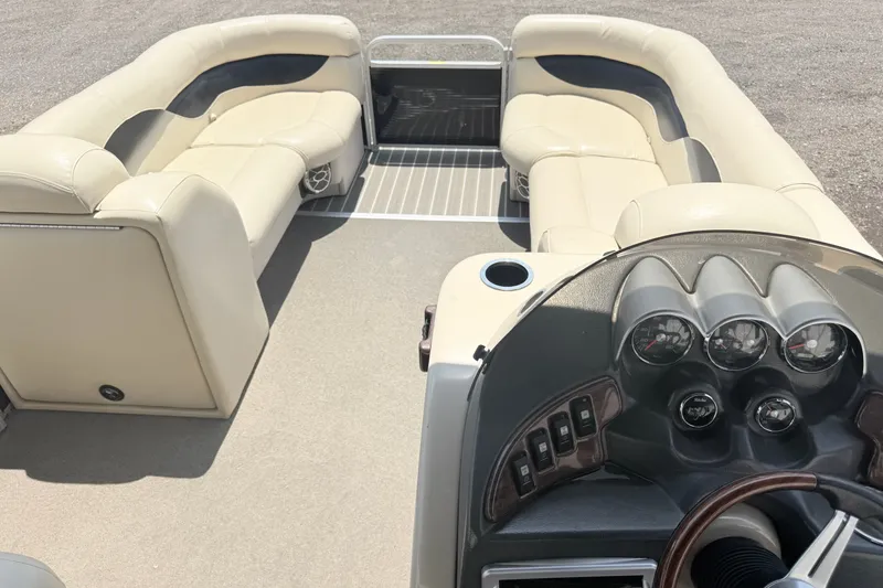 Slide: The Image of 2013 AquaPatio 240 RS boat interior with beige seating and dashboard controls. - 16