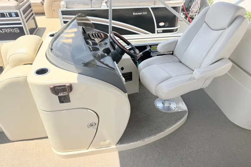 Slide: The Image of Captain's chair and helm of 2013 AquaPatio 240 RS pontoon boat, featuring steering wheel and controls. - 7