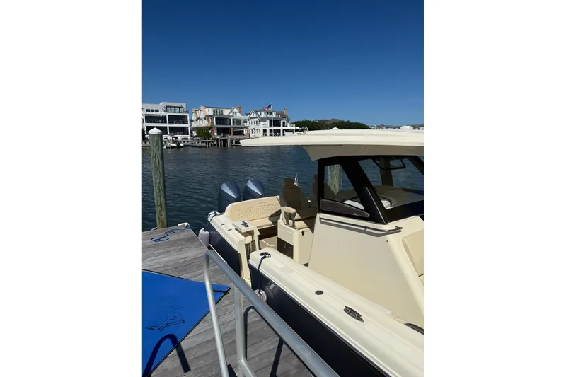Slide: The Image of 2019 Chris-Craft Catalina 30 docked by waterfront homes under clear blue sky. - 3