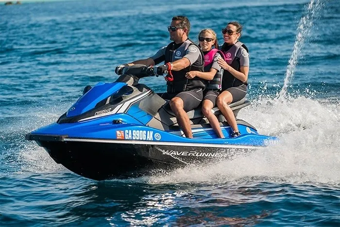 Slide: The Image of A blue 2018 Yamaha EX Deluxe jet ski with three people riding on it, gliding over the water. - 10
