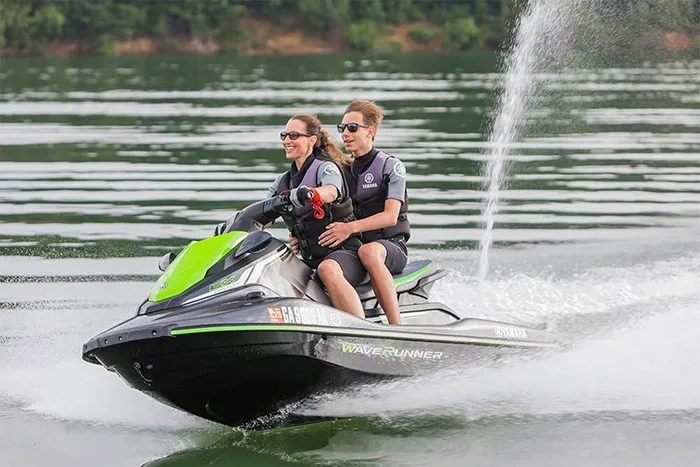 Slide: The Image of Two people ride a Yamaha EX Deluxe jet ski across calm water. - 9