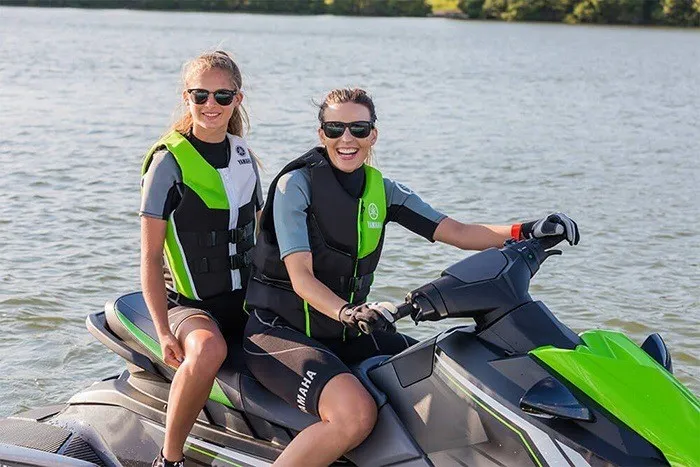 Slide: The Image of Two people on a Yamaha EX Deluxe jet ski on a lake, both wearing life jackets. - 11
