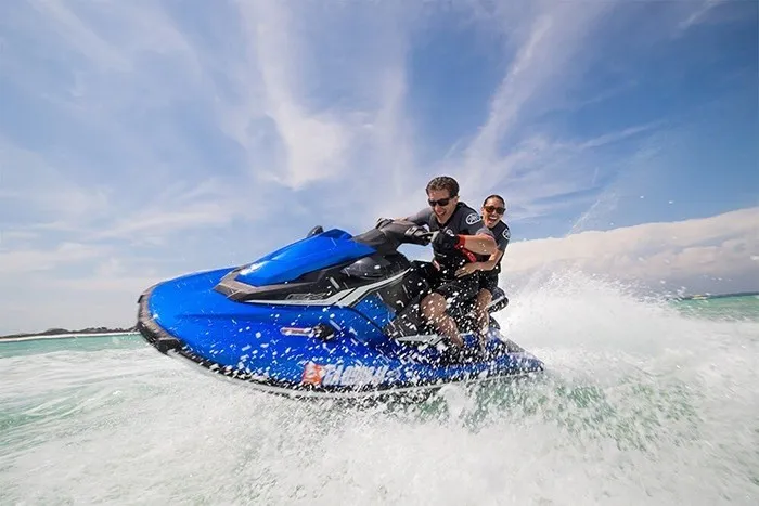 Slide: The Image of Two people ride a blue Yamaha EX Deluxe jet ski across the water. - 12