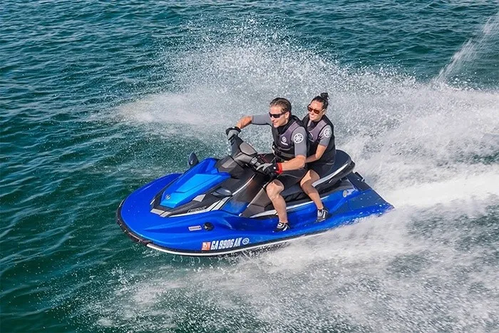 Slide: The Image of Two people ride a blue Yamaha EX Deluxe jet ski across the water. - 7