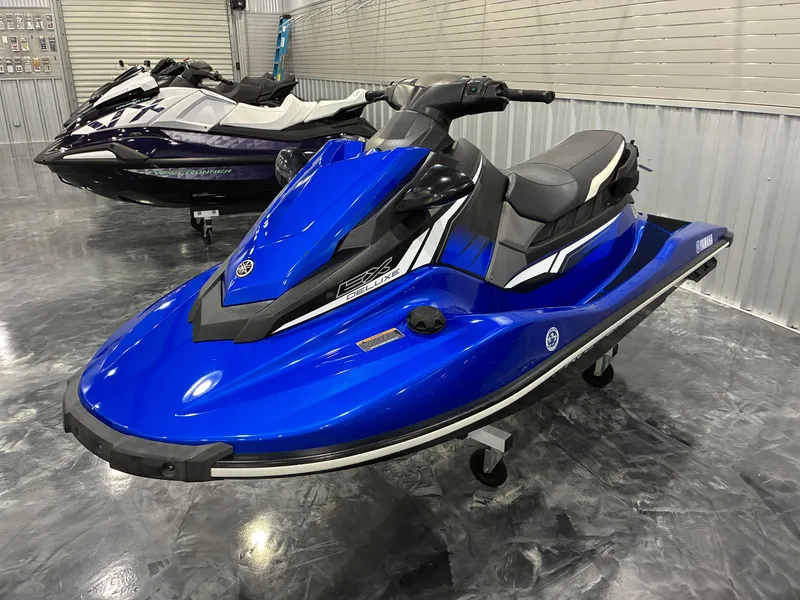 Slide: The Image of A blue 2018 Yamaha EX Deluxe jet ski sits indoors on a shiny floor. - 2