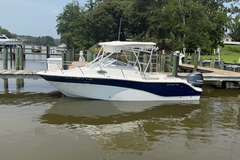 Slide: The Image of 2013 Sea Fox 256 Voyager boat docked on calm water, surrounded by greenery. - 3