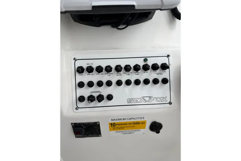 Slide: The Image of Control panel of a 2013 Sea Fox 256 Voyager boat, showing switches and capacity label. - 10