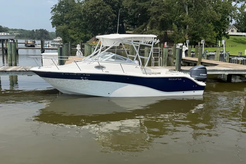 Slide: The Image of 2013 Sea Fox 256 Voyager boat docked in a serene marina setting. - 1