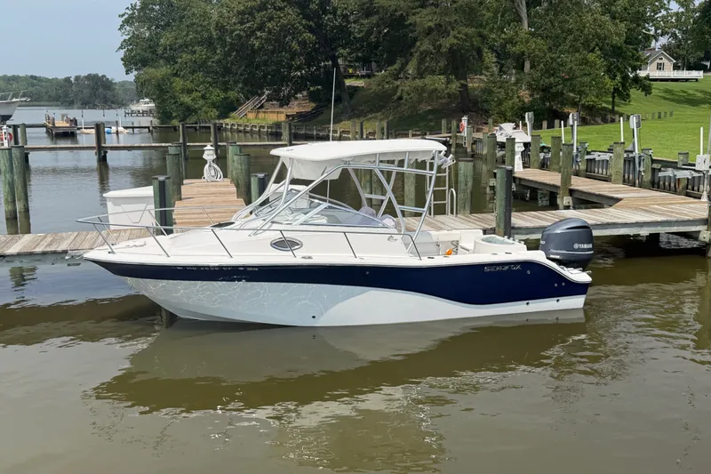 Slide: The Image of 2013 Sea Fox 256 Voyager boat docked at a marina with lush greenery. - 4