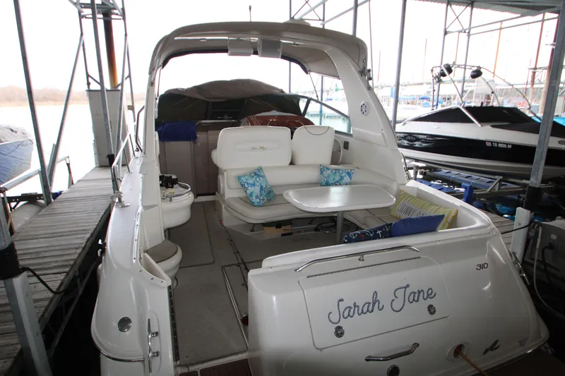 Slide: The Image of 2000 Sea Ray 310 Sundancer docked, featuring spacious seating and table. - 6