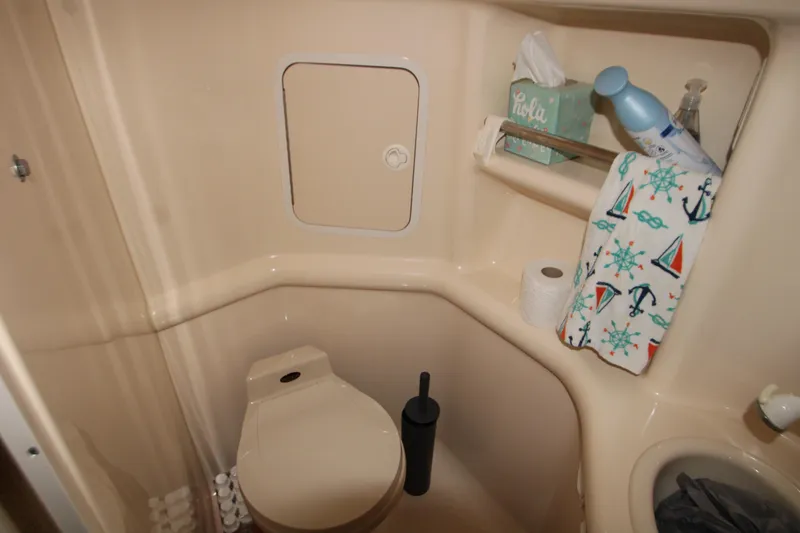 Slide: The Image of Bathroom interior of 2000 Sea Ray 310 Sundancer boat with toilet and storage shelves. - 27