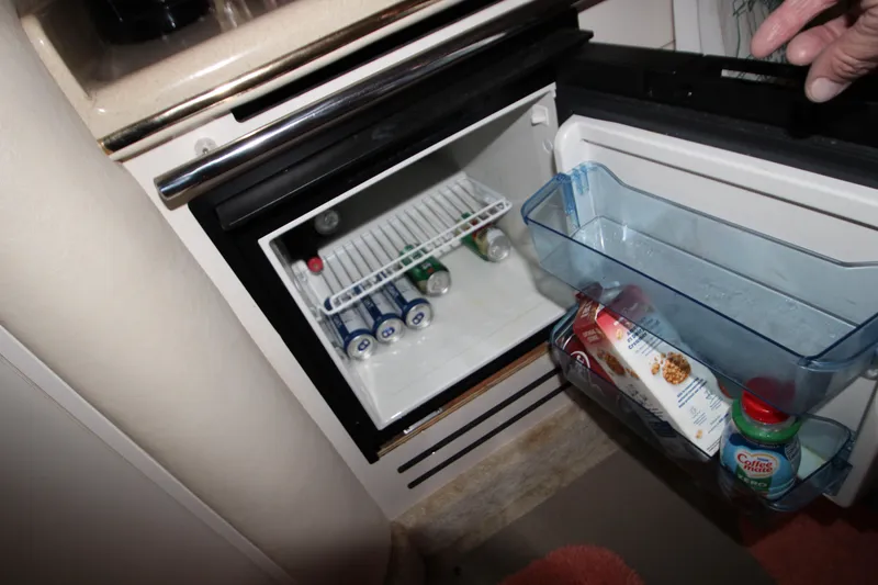 Slide: The Image of Mini fridge inside 2000 Sea Ray 310 Sundancer yacht, stocked with beverages and snacks. - 26