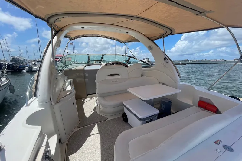 Slide: The Image of 2003 Sea Ray 360 Sundancer yacht interior with seating and table, docked at marina under blue sky. - 9