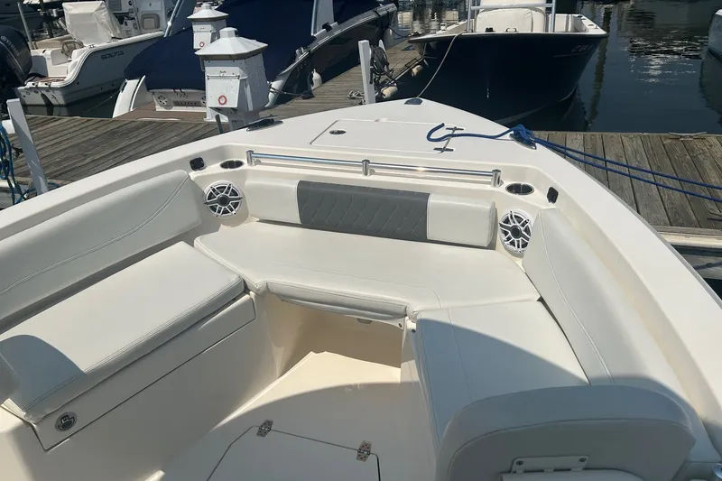 Slide: The Image of 2024 Cobia 240 Center Console boat interior with seating and speakers at a marina. - 7