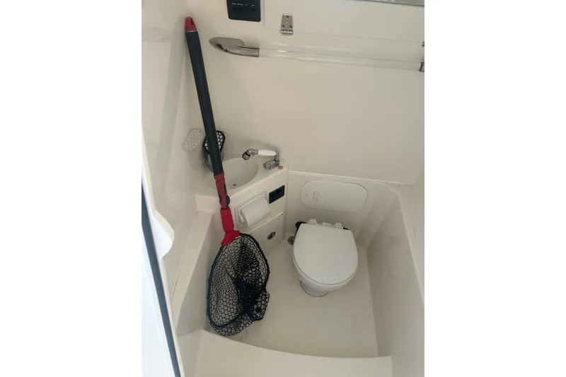 Slide: The Image of 2024 Cobia 240 Center Console boat interior with toilet and fishing net. - 15