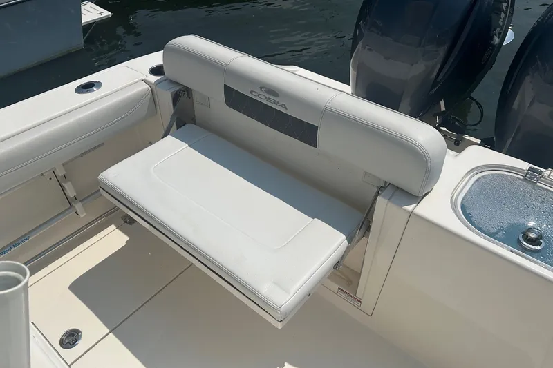 Slide: The Image of 2024 Cobia 240 Center Console boat with foldable rear seating and dual engines. - 11