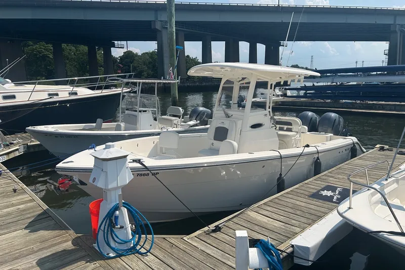 The Image of 2024 Cobia 240 Center Console boat docked at marina under bridge. - 0
