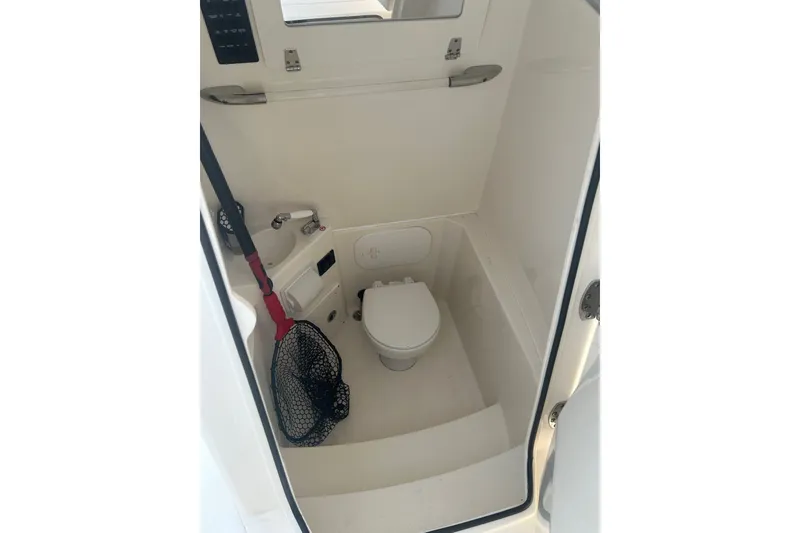 Slide: The Image of 2024 Cobia 240 Center Console boat interior with compact marine toilet and storage. - 16