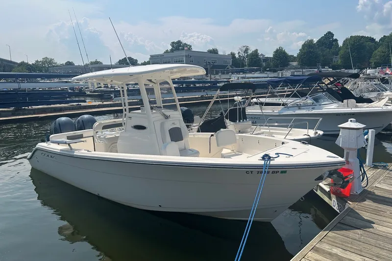 Slide: The Image of 2024 Cobia 240 Center Console boat docked at a marina under a clear sky. - 3