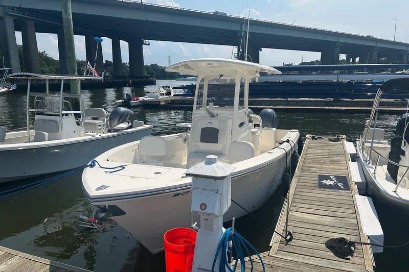 Slide: The Image of 2024 Cobia 240 Center Console boat docked at marina under bridge. - 1
