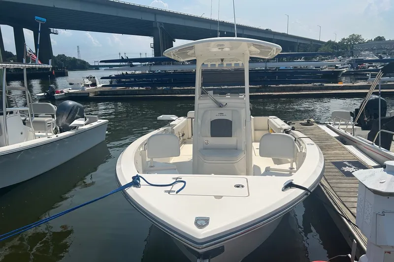 Slide: The Image of 2024 Cobia 240 Center Console boat docked at marina under bridge. - 2