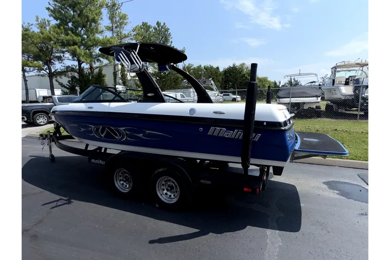 Slide: The Image of 2008 Malibu iRide boat on trailer, parked outdoors under clear sky. - 5