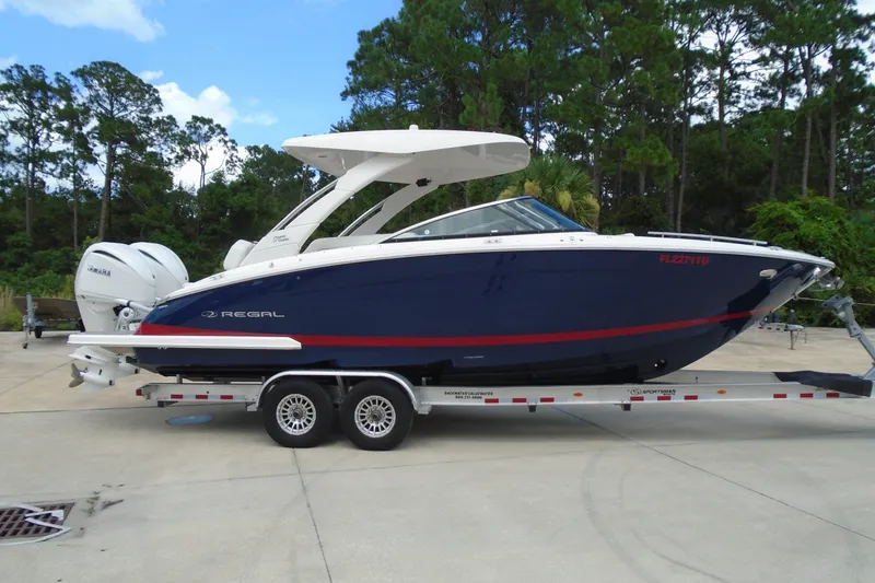 Slide: The Image of 2024 Regal LX9 boat on trailer, blue hull, dual Yamaha engines, parked outdoors. - 1
