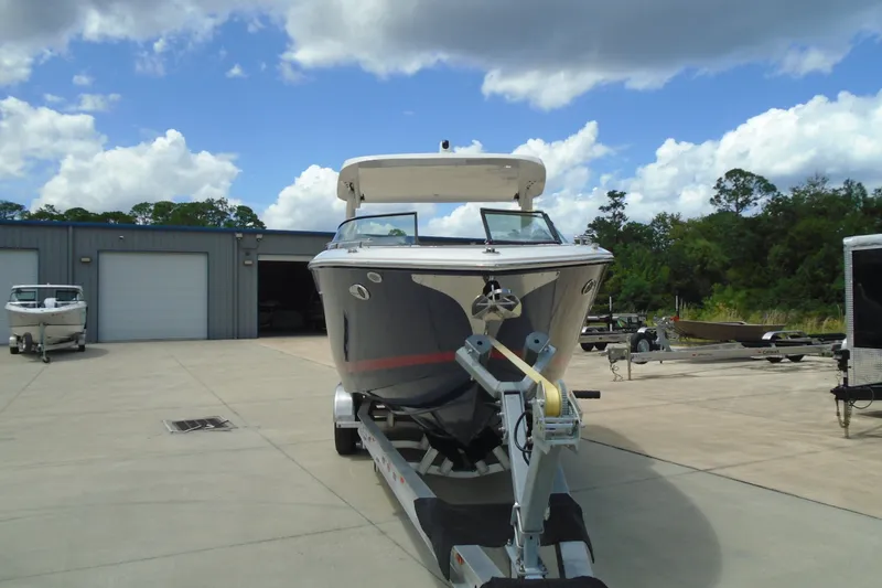 Slide: The Image of 2024 Regal LX9 boat on trailer, parked outside a storage facility under a cloudy sky. - 2