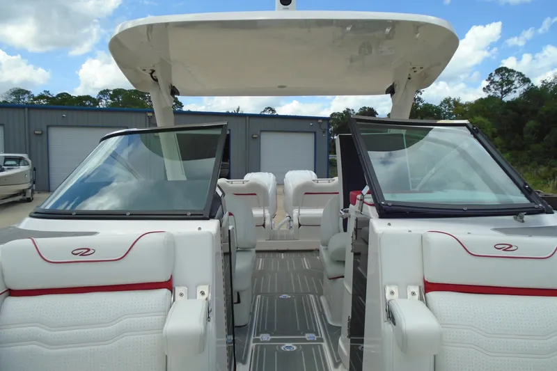 Slide: The Image of 2024 Regal LX9 boat interior with white seating and red accents, under a clear blue sky. - 13