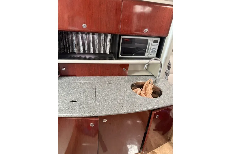 Slide: The Image of 2005 Formula 370 Super Sport boat kitchen with microwave, sink, and wooden cabinetry. - 33