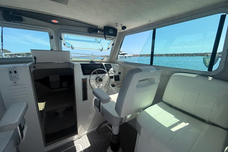 Slide: The Image of 2022 Parker 2520 XLD Sport Cabin interior with steering wheel and seating, overlooking marina. - 35