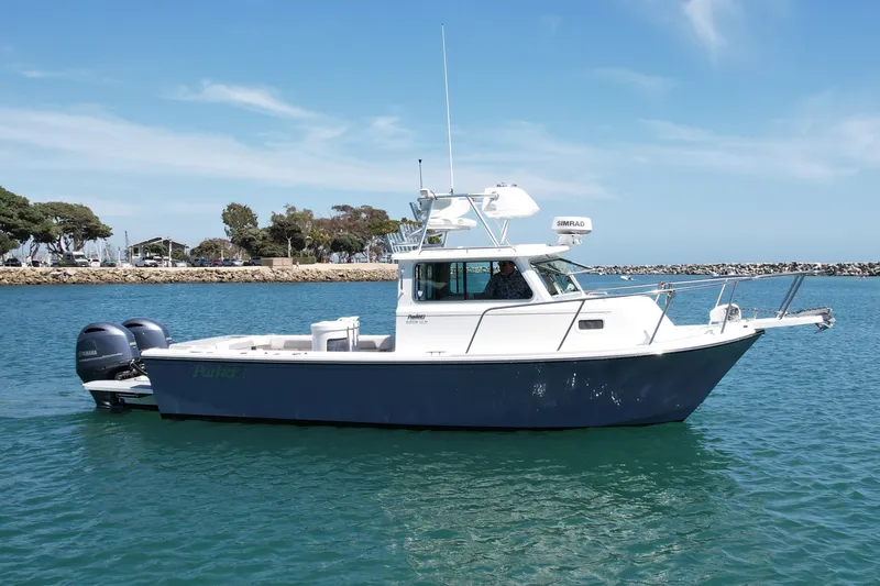 The Image of 2022 Parker 2520 XLD Sport Cabin boat on calm water, clear sky background. - 1