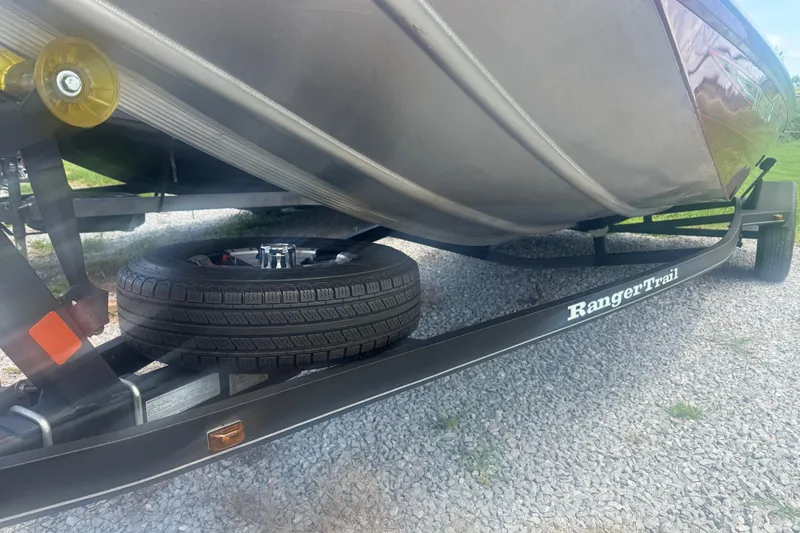 Slide: The Image of 2018 Ranger RT188 boat on Ranger Trail trailer with spare tire, parked on gravel. - 5