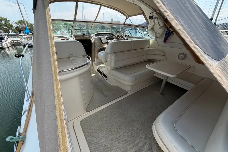 Slide: The Image of 1999 Sea Ray Sundancer 330 interior with seating, table, and helm in marina setting. - 11