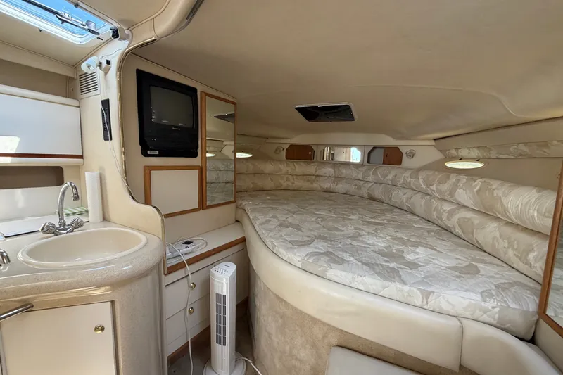 Slide: The Image of 1999 Sea Ray Sundancer 330 cabin interior with bed, sink, and TV. - 27