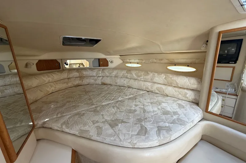Slide: The Image of 1999 Sea Ray Sundancer 330 cabin interior with plush bedding and elegant wood accents. - 28