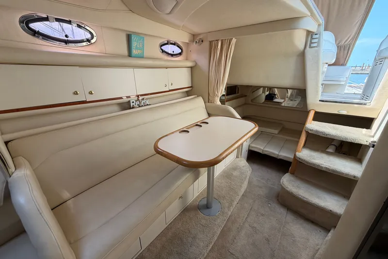 Slide: The Image of 1999 Sea Ray Sundancer 330 cabin interior with beige seating, table, and stairs. - 29