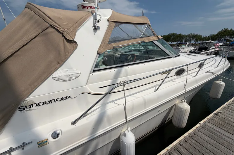 Slide: The Image of 1999 Sea Ray Sundancer 330 docked, featuring beige canopy and sleek white hull design. - 10