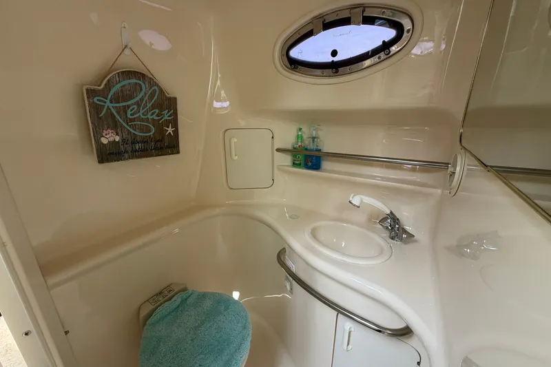 Slide: The Image of 1999 Sea Ray Sundancer 330 bathroom with sink, porthole, and "Relax" sign. - 31