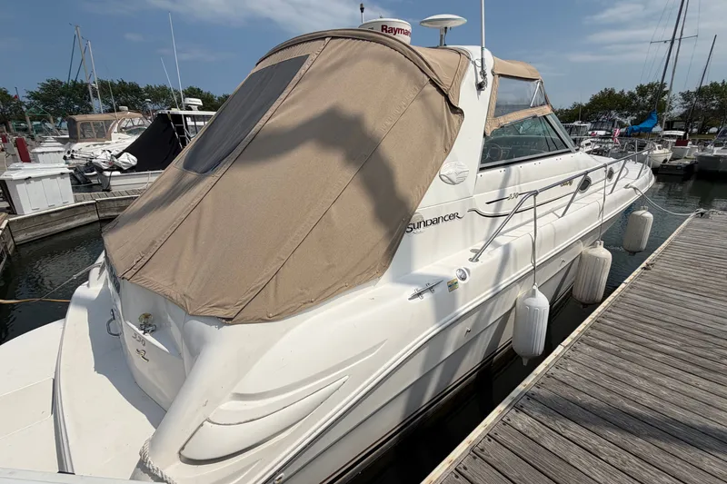 Slide: The Image of 1999 Sea Ray Sundancer 330 docked at marina, featuring beige canopy and sleek design. - 5