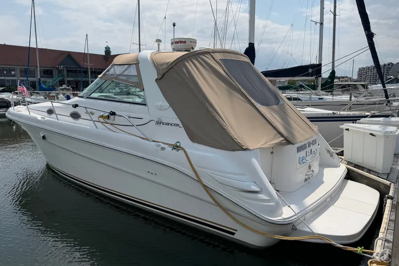 Slide: The Image of 1999 Sea Ray Sundancer 330 yacht docked at marina, featuring beige canopy and sleek design. - 2