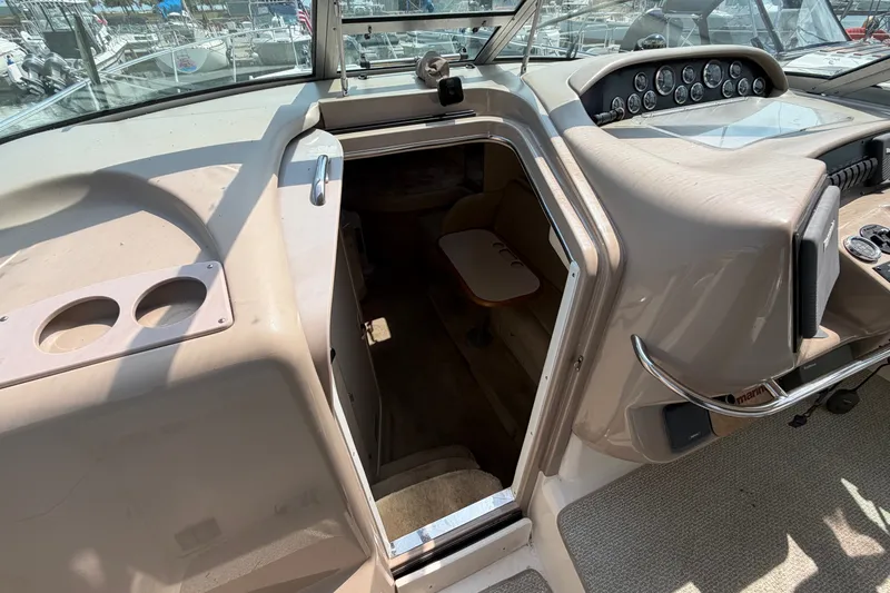 Slide: The Image of 1999 Sea Ray Sundancer 330 cockpit with cabin entrance, showcasing helm controls and seating area. - 24