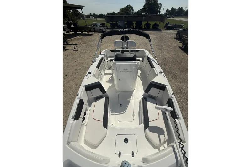 Slide: The Image of 2023 Tahoe 2150 CC boat interior with seating and steering console, parked outdoors. - 8