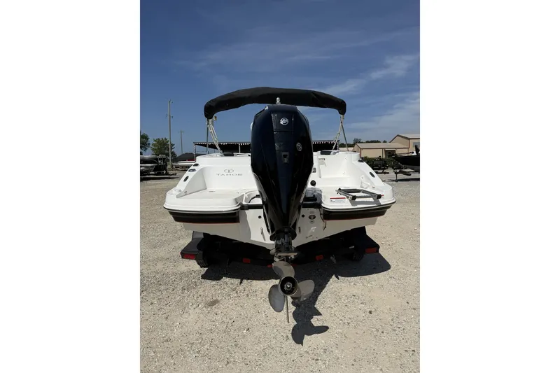 Slide: The Image of 2023 Tahoe 2150 CC boat with outboard motor, parked on gravel under clear sky. - 5