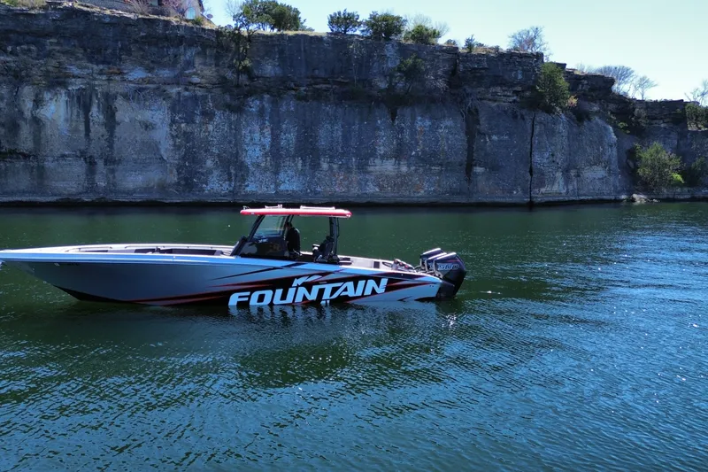 Slide: The Image of 2024 Fountain 38 SC boat cruising on a scenic lake with rocky cliffs. - 7