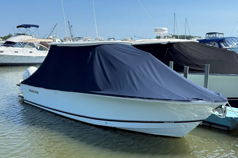 Slide: The Image of 2024 Regulator 28 boat docked with a protective cover in a marina. - 25