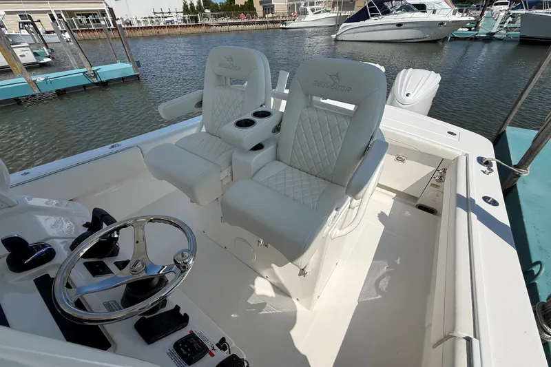 Slide: The Image of 2024 Regulator 28 boat interior with white cushioned seats and steering wheel at marina. - 17